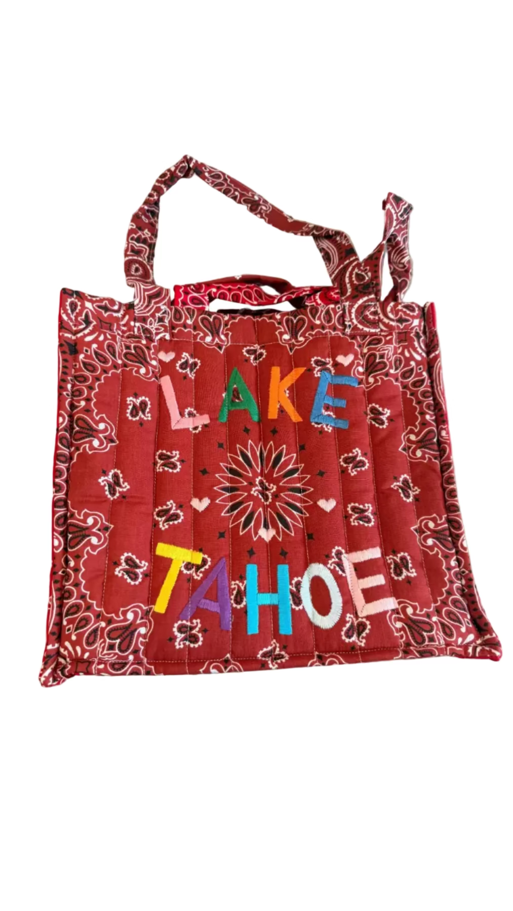 Red bandana-patterned tote bag with 'Lake Tahoe' text on a concrete surface