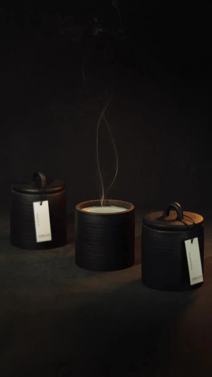 Three black ceramic containers with lids on a dark background