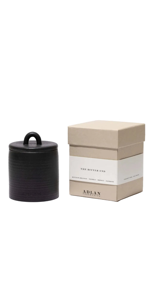 Black cylindrical container with a lid next to a beige box labeled 'The Bitter End' by 'Adlan' on a white background