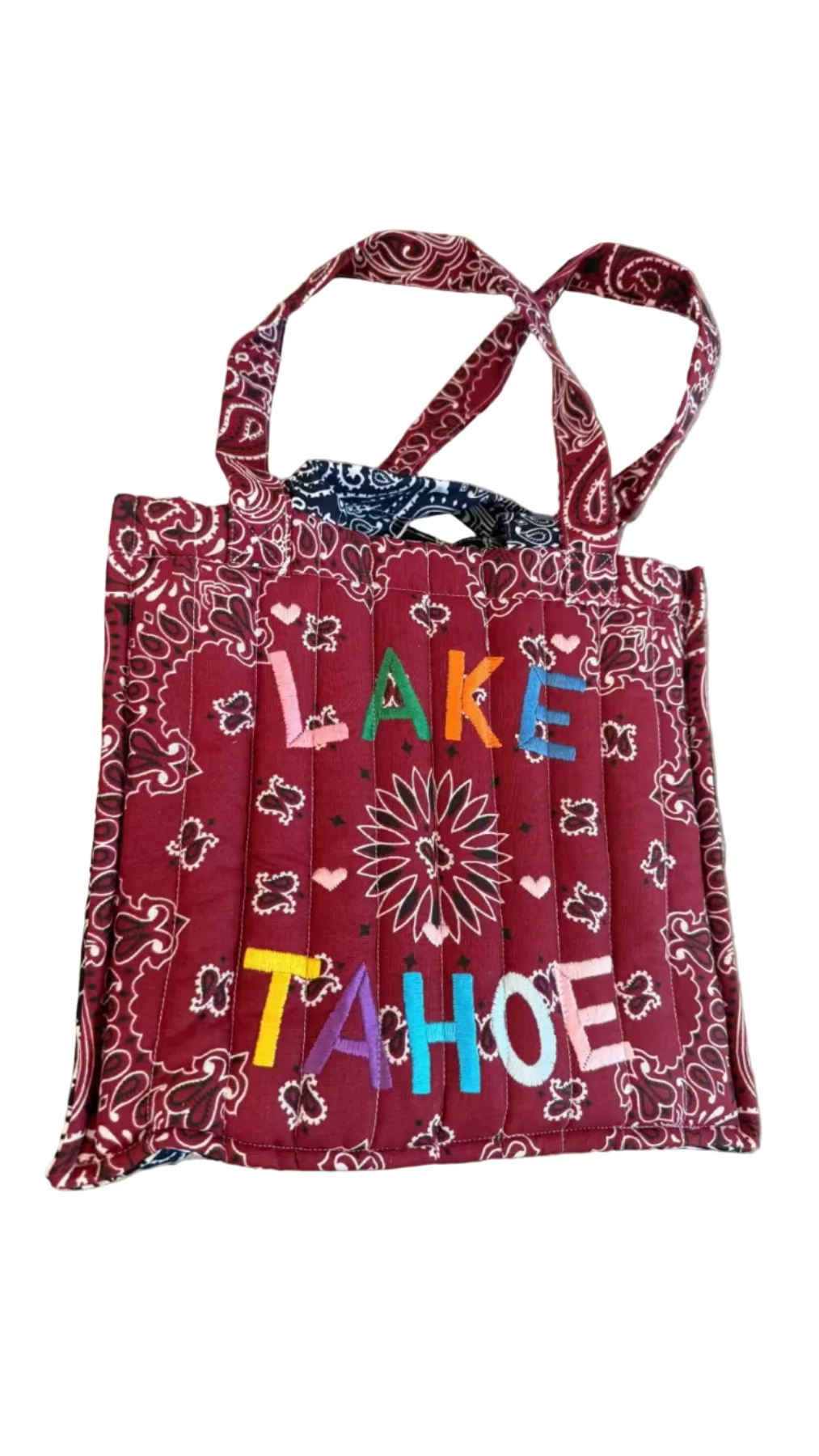 Red bandana-patterned tote bag with 'Lake Tahoe' text on a concrete surface